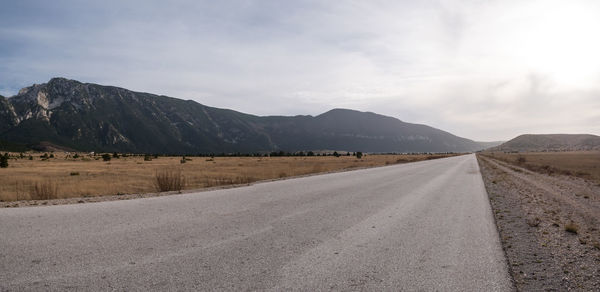 Road leading towards mountains against sky