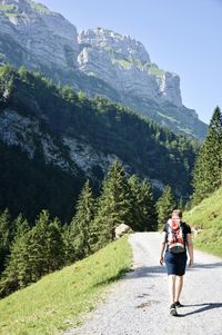 Rear view of man with backpack walking on road