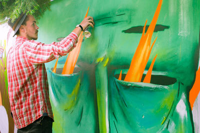 Young man spray painting graffiti on surrounding wall