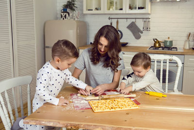 Mother with children sons making cookies in the kitchen