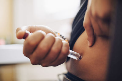 Close-up of businessman injecting insulin in abdomen in office