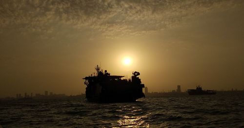 Silhouette ship in sea against sky during sunset