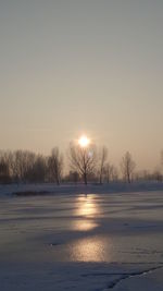 Scenic view of frozen lake against clear sky during sunset