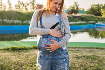 Pregnant woman standing by lake