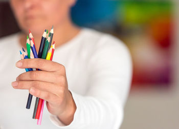 Midsection of woman holding colored pencils