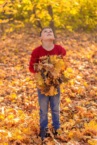 Full length of teenage girl holding autumn leaves