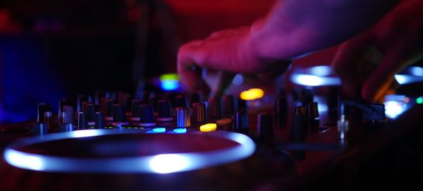 Cropped hand of dj adjusting knobs on sound mixer