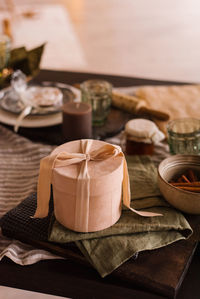 Stylish round powder-colored gift box with a ribbon and a bow stands on the festive table