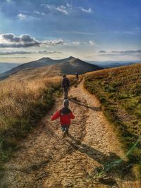 Rear view of child walking on mountain trail