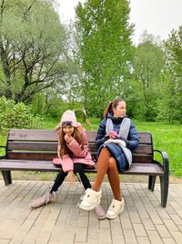 Full length of woman sitting on bench in park