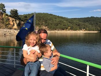 Happy father with son and daughter on boat sailing in river