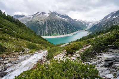 Scenic view of stream amidst snowcapped mountains against sky