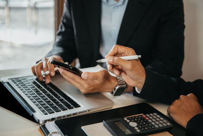 Midsection of businessman using laptop at office