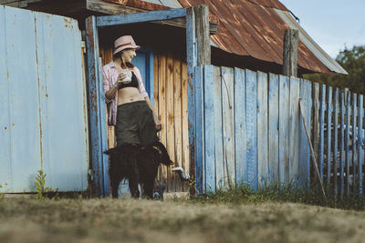 Woman with glass of milk standing with dog at doorway