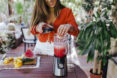 Midsection of woman with drink on table