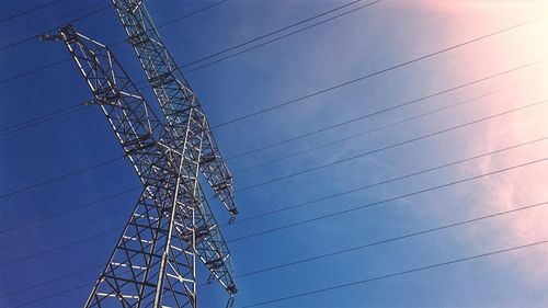 Low angle view of electricity pylon against blue sky