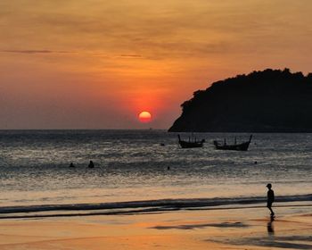 Silhouette man on beach against sky during sunset