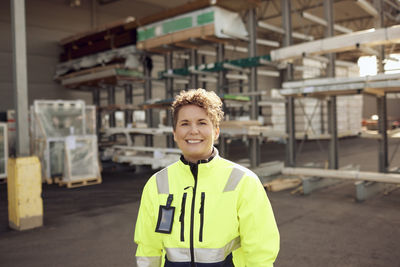 Portrait of smiling female worker standing in front of distribution warehouse