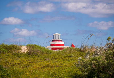 Lighthouse on field against sky