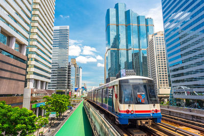 Railroad tracks amidst buildings in city against sky