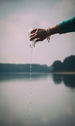 Close-up of hand against blurred lake