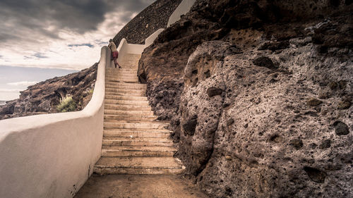 Narrow footpath leading to sea against sky