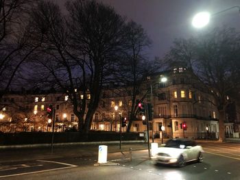 Cars on street against illuminated buildings in city at night