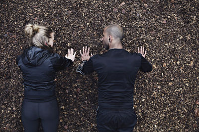 Directly above shot of couple doing plank exercise in forest