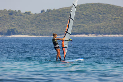 Man with umbrella on sea against mountain