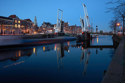 Bridge over river against clear sky in city at dusk