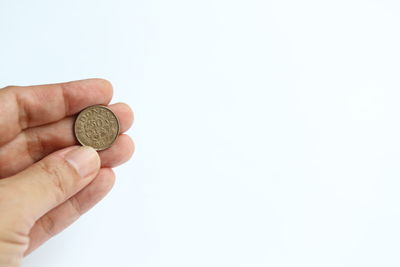 Close-up of hand holding coins against white background