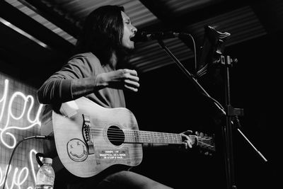 Low angle view of man singing and playing guitar