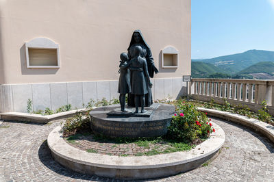 Statue by fountain against building