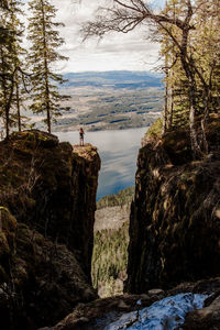 Man standing on rock against sky