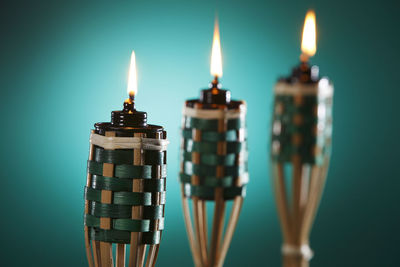 Close-up of illuminated tiki torches against blue background