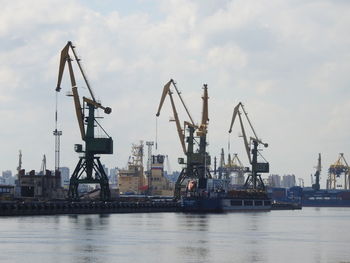 Cranes at commercial dock against sky