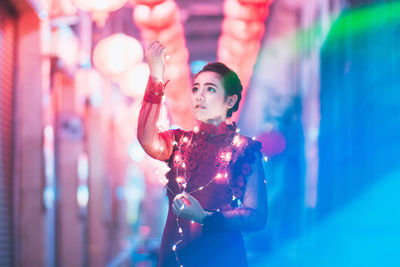 Young woman holding multi colored string lights during event