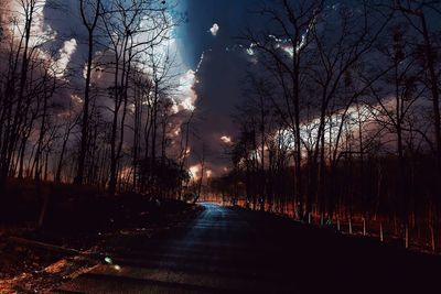 Road amidst bare trees against sky