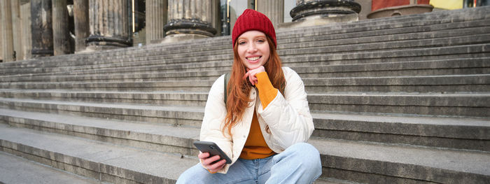 Portrait of woman standing against steps