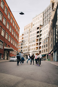 Full length of carefree friends dancing on street in city