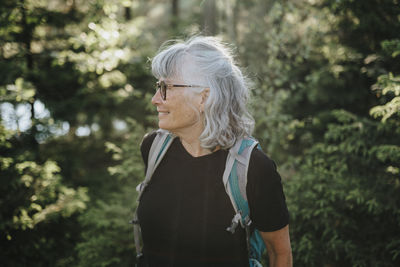 Senior woman looking around in forest