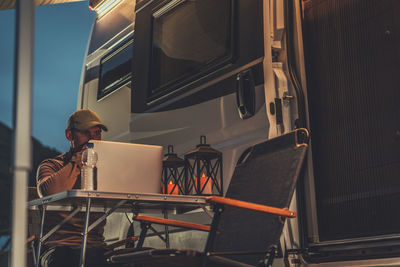 Man using laptop sitting by bus outdoors