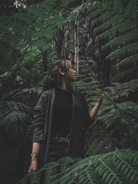 Woman standing by trees in forest