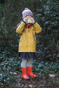 Full length of girl photographing on field