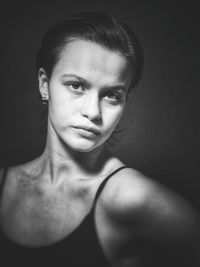 Close-up portrait of young woman against black background