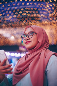 Portrait of beautiful young woman wearing eyeglasses at night