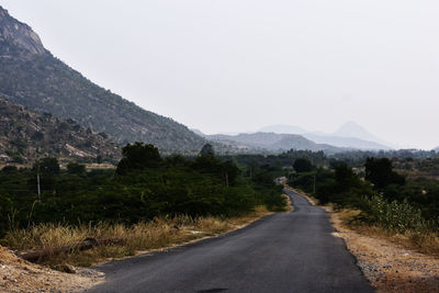 Empty road along landscape and mountains against sky