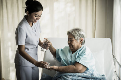 Smiling nurse giving dose to senior woman at hospital