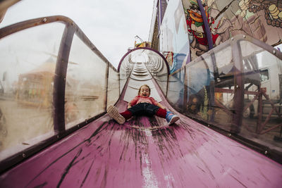 Low angle view of happy girl screaming while sliding at amusement park