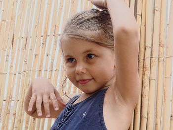 Cute girl looking away while standing by fence